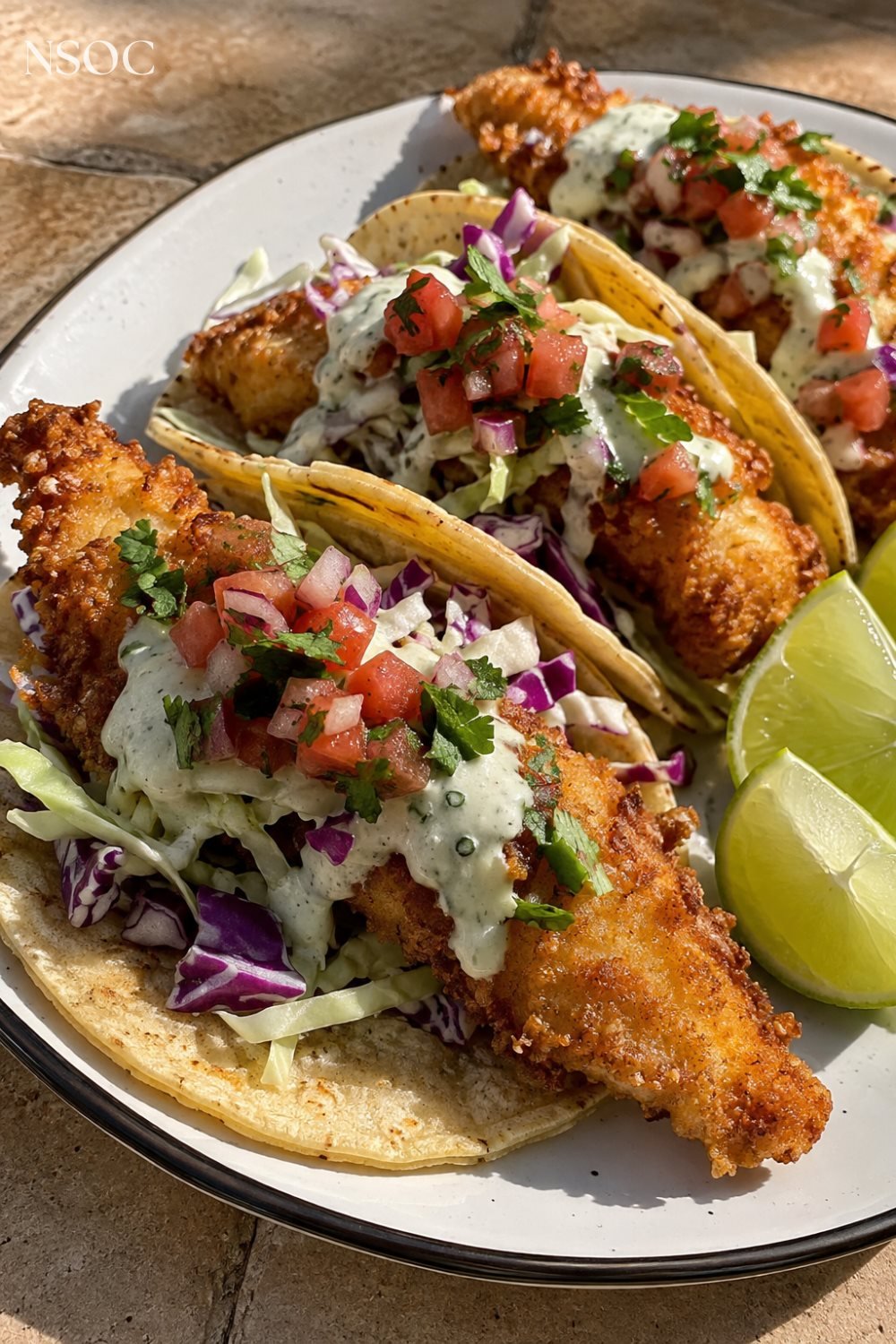 Vertical Pinterest pin of crispy fish tacos with cabbage slaw and lime