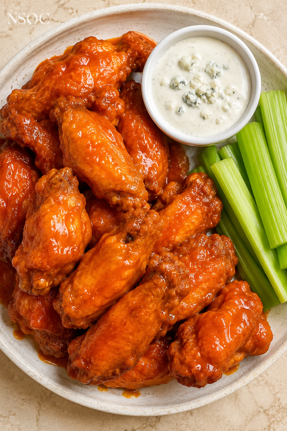 Vertical Pinterest pin of hot buffalo wings served with blue cheese dip and celery