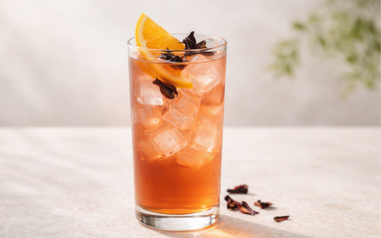 hibiscus ginger orange white tea cooler served over ice with orange wedge