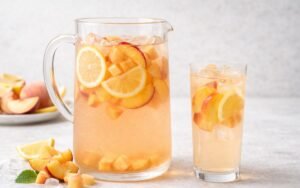 pitcher of peach lemon infused water with sliced peaches and lemons