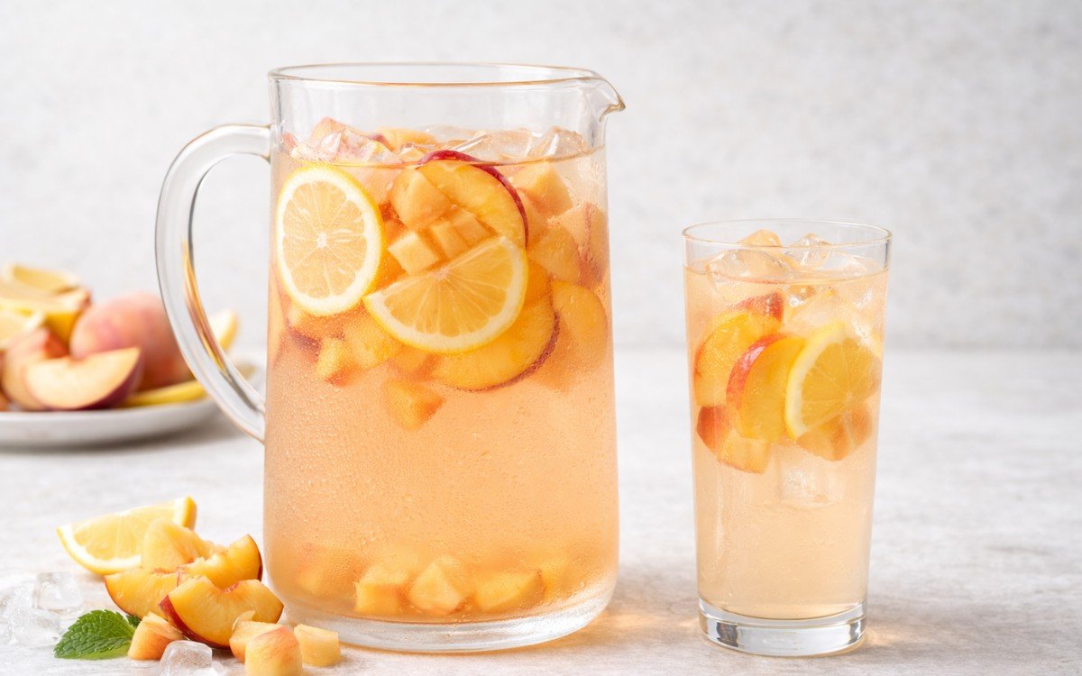 pitcher of peach lemon infused water with sliced peaches and lemons