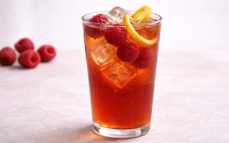 raspberry iced black tea served over ice with fresh raspberries and lemon peel twist