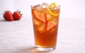 strawberry iced black tea served over ice with fresh strawberry slices and lemon peel twist