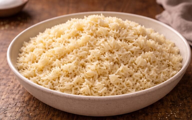 Close-up of fluffy butter rice in a white bowl with a fork, showing golden grains and melted butter