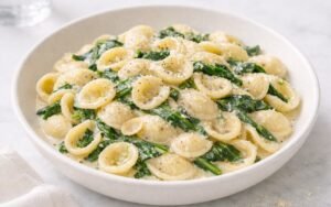Lemon ricotta spinach orecchiette with Parmesan and black pepper in a white bowl