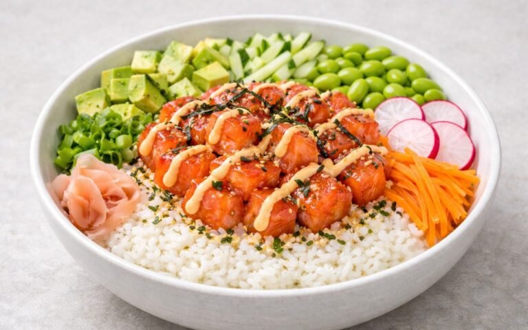 Colorful salmon poke bowl with fresh raw salmon, avocado, edamame, cucumber, and radishes over seasoned sushi rice drizzled with spicy mayo