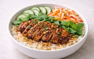 Vietnamese lemongrass chicken rice bowl with grilled chicken, pickled vegetables, fresh herbs, and nuoc cham dressing