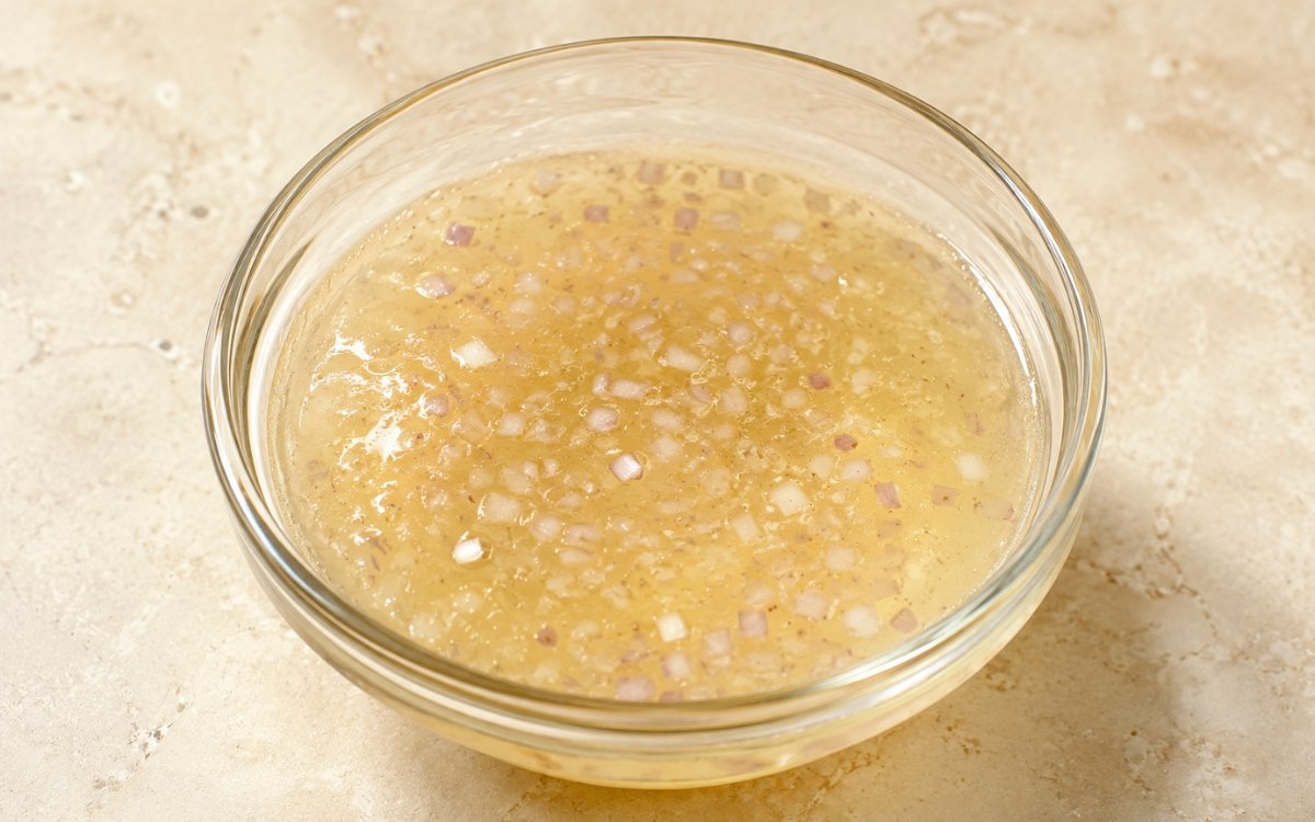 Champagne vinegar dressing in a small glass bottle showing pale golden, delicate dressing with fine texture