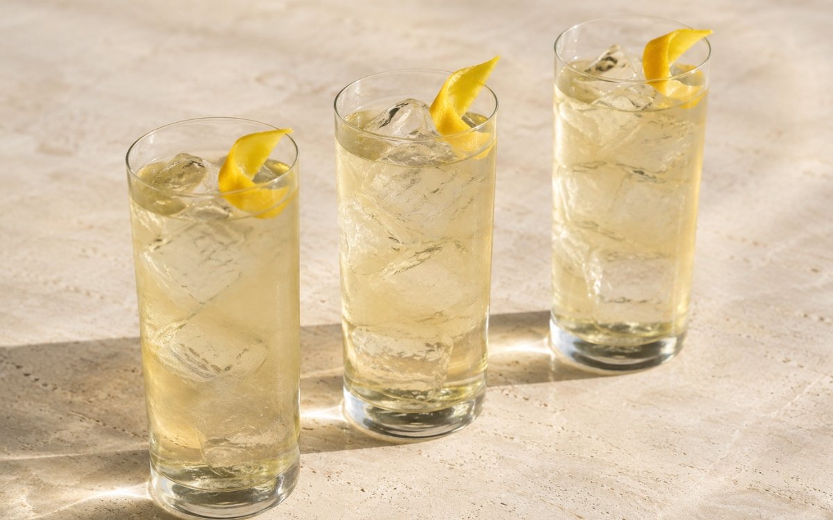 Cold brew white tea in a tall glass showing very pale clear still drink over ice with a lemon peel twist on marble surface