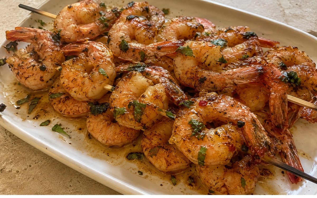 Garlic shrimp skewers with charred edges drizzled in garlic herb butter