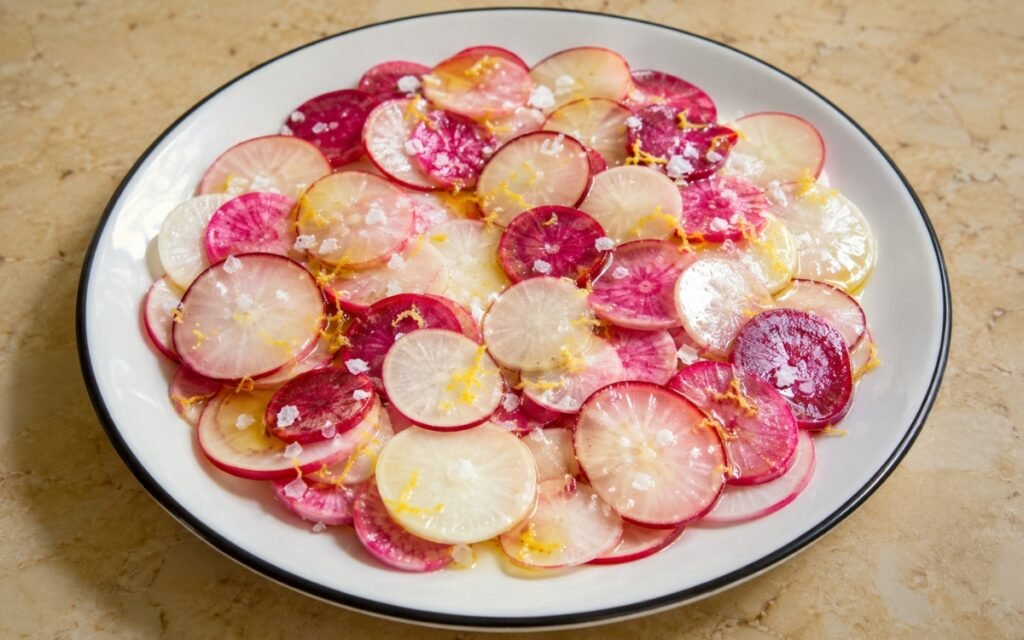 Radish lemon olive oil salad with thinly sliced radishes, fresh herbs, and lemon dressing in a white bowl