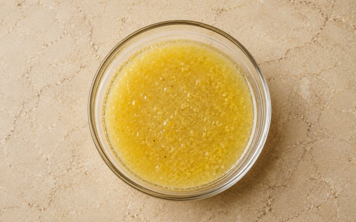 Simple lemon vinaigrette in a small glass jar showing bright yellow dressing with visible emulsion