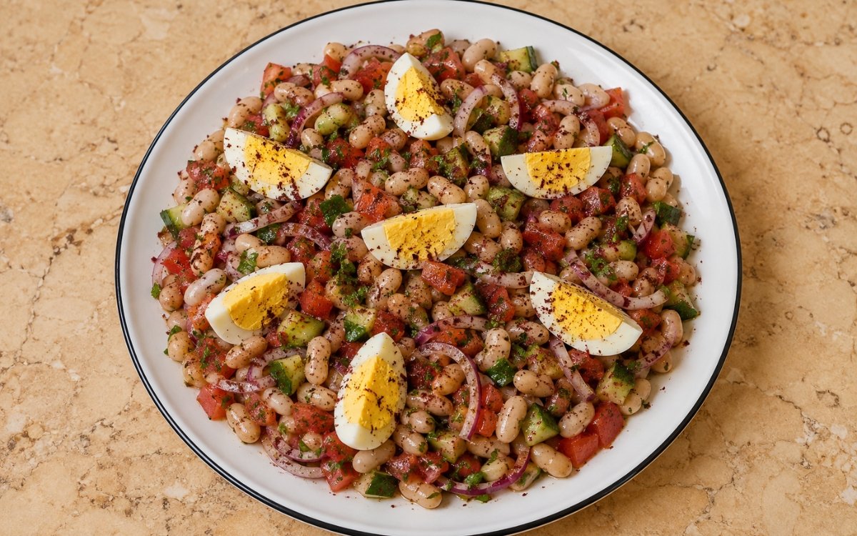 Bowl of Turkish piyaz white bean salad with tomatoes, onions, hard-boiled eggs, and sumac dressing