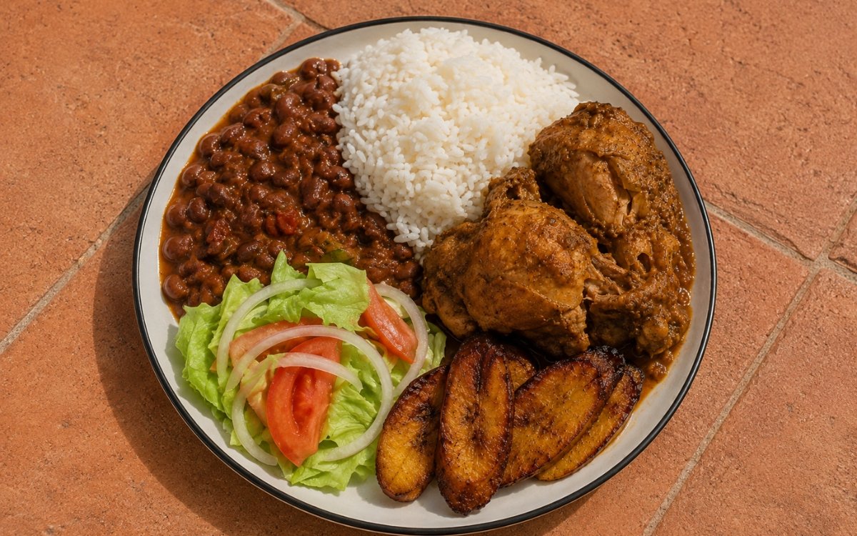La Bandera Dominicana plate showing white rice, stewed red beans, braised chicken, fried plantains, and fresh salad kept in distinct sections, on marble surface