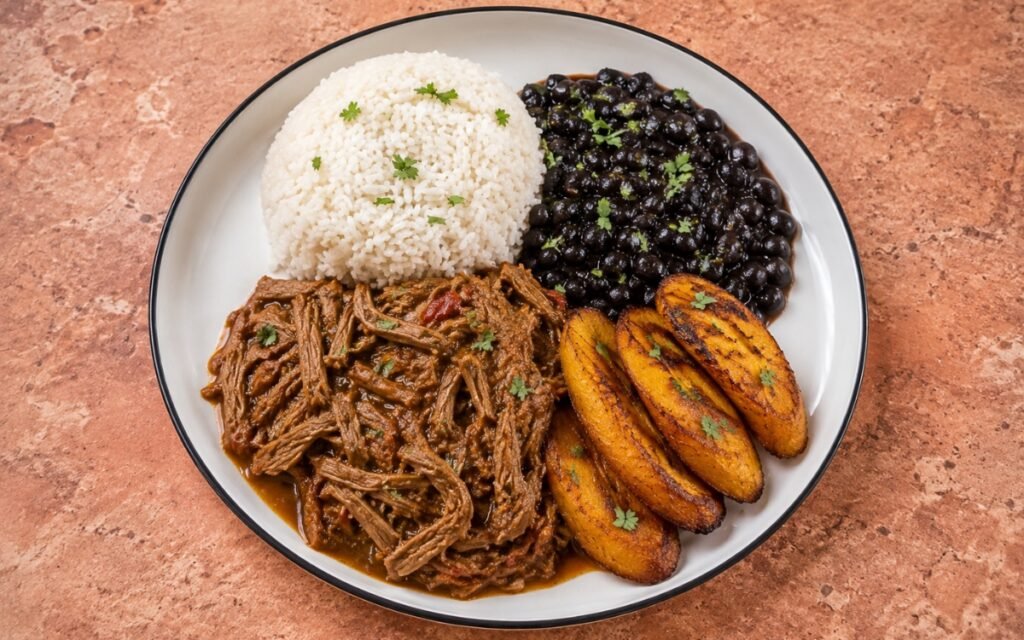 Pabellón Venezolano plate showing shredded beef, white rice, black beans, and sweet fried plantains kept in distinct sections, on marble surface